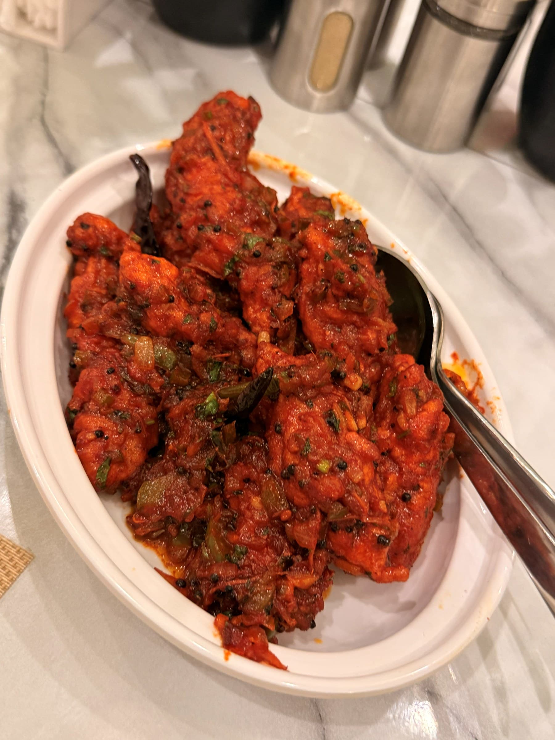 Chilli chicken glazed in a fiery red masala, served in a white oval dish