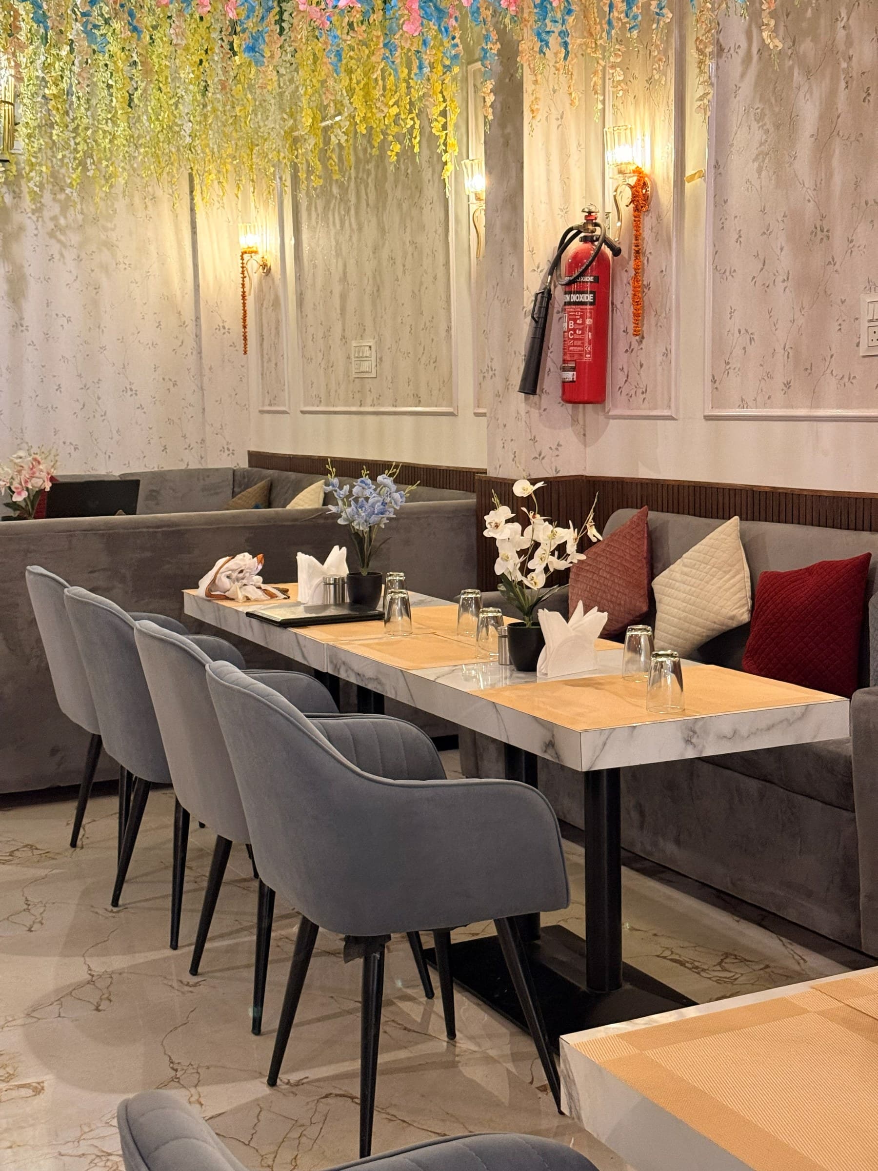 Marble-top tables and velvet chairs beneath cascading flowers